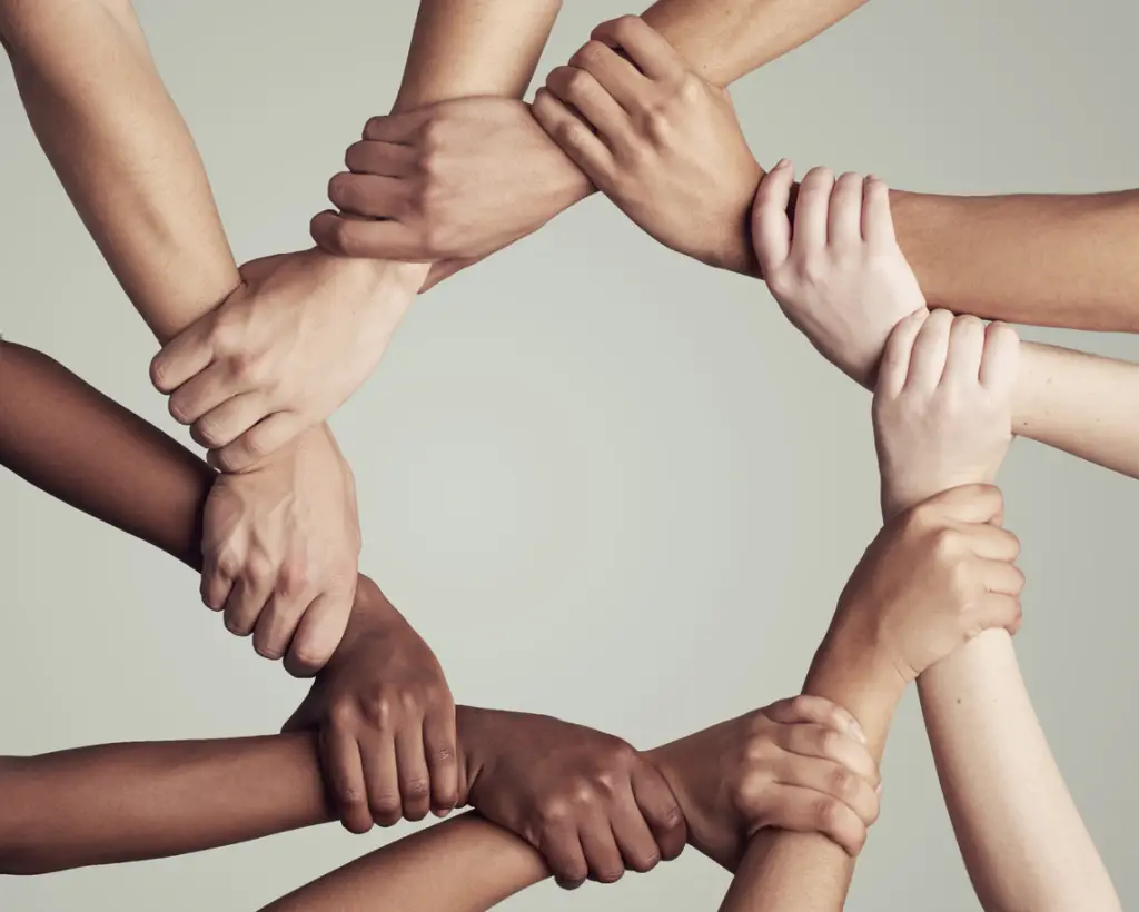 Mãos e braços de pessoas diversas unidos em círculo, simbolizando união e solidariedade nos Jogos Solidários América.